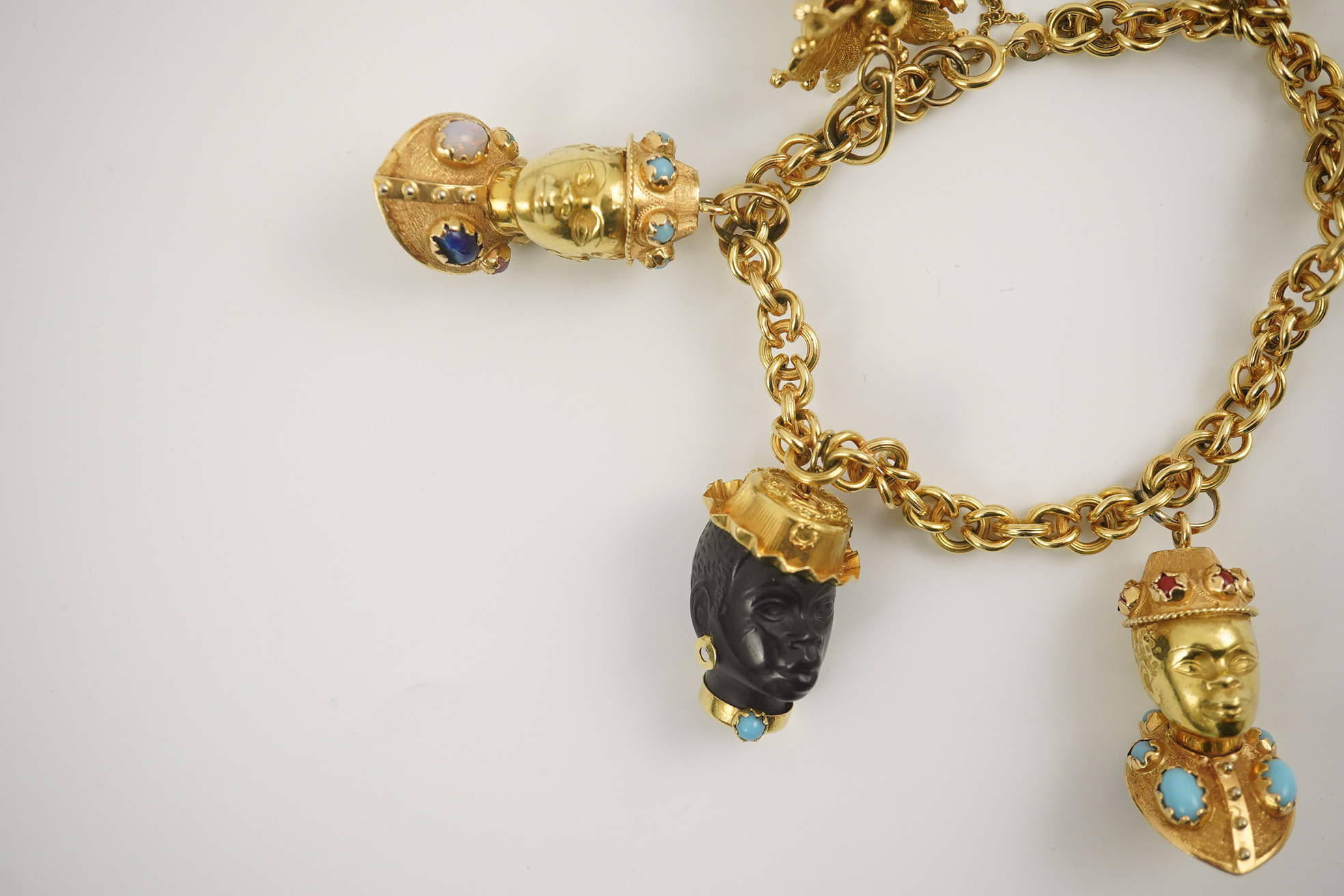 A late 20th century Italian 18k gold charm bracelet, hung with six assorted Italian 18k gold and gem set mounted blackamoor busts, together with a matching brooch